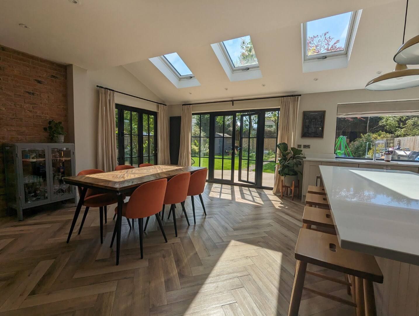 Bright open-plan kitchen and dining extension with skylights, bi-fold doors and herringbone flooring